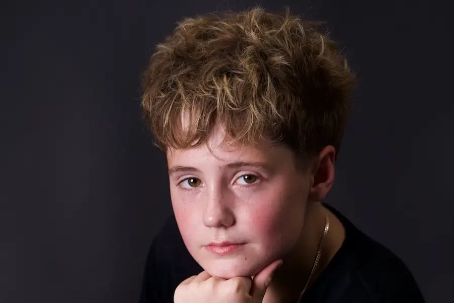 A model pose of a teenage boy with dramatic lighting at Studio Exposja by Exposja Photography