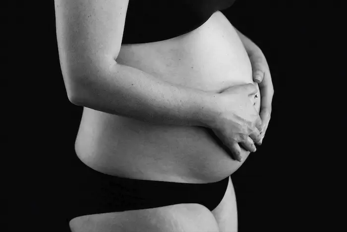 Pregnant mother with black underwear touching her baby bump at Studio Exposja for Exposja Photography
